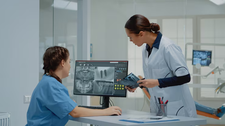Dentist and assistant reviewing panoramic radiographs on a practice workstation